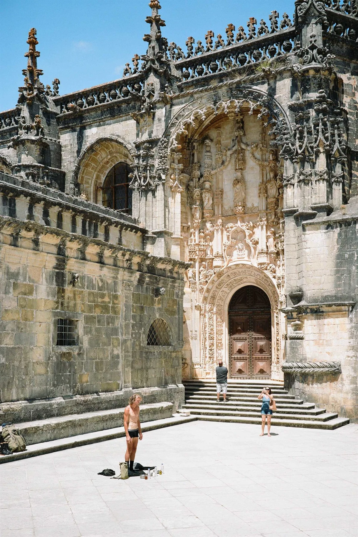GABRIEL: nackter Mann steht auf dem Vorplatz einer reich verzierten Klosterkirche in Portugal