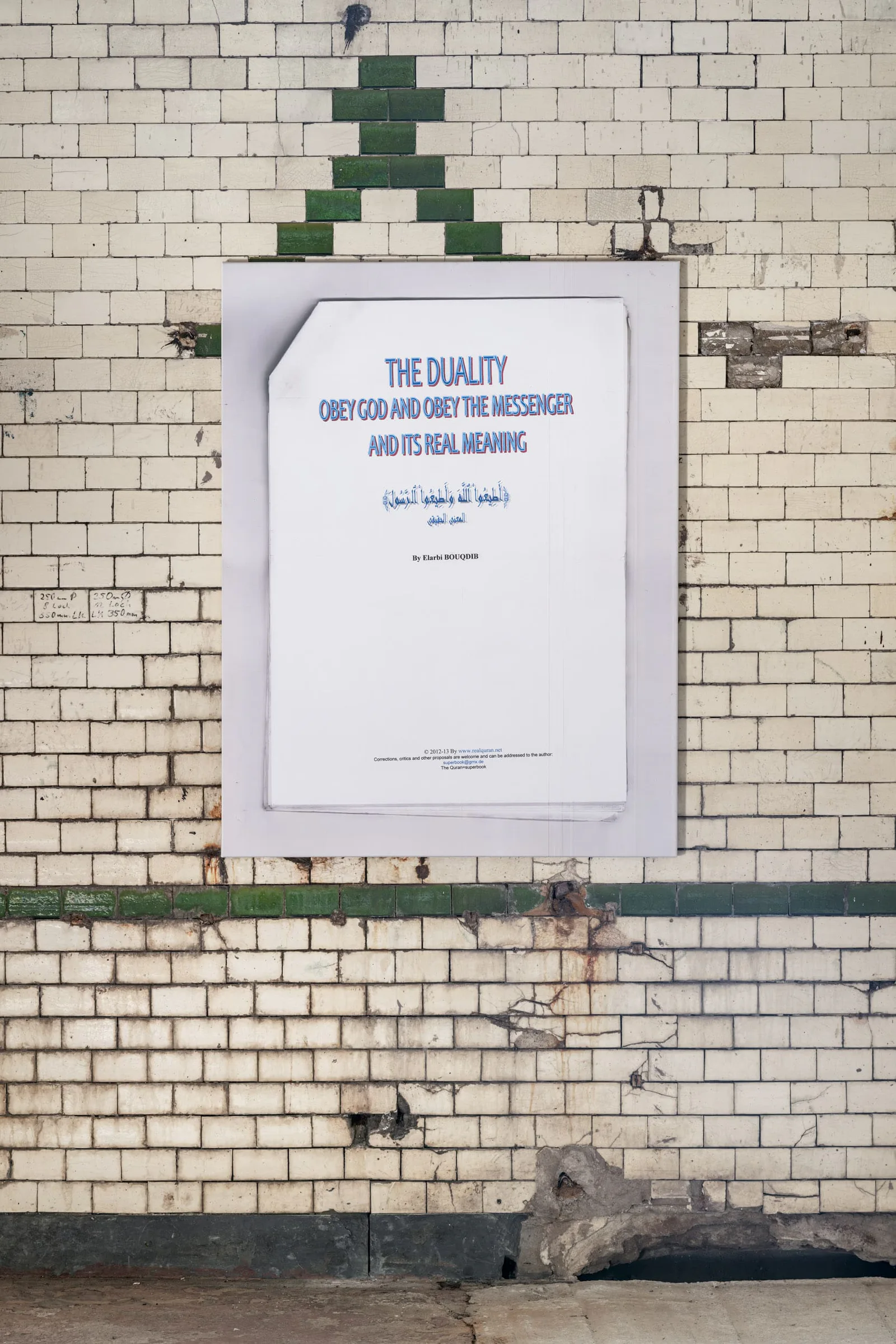 Neue Erinnerungen: Plakat „The Duality“ mit arabischem Text an einer Kachelwand unter einem grünen Dreieck