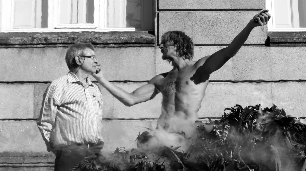 GABRIEL während der Performance Unicorn V Eucalypto in Pontevedra 2016: ein Mann mit nacktem Oberkörper streckt den Arm aus, ein Mann mit Brille daneben, Schwarz-Weiß, Foto Laura Fociños Mantecón