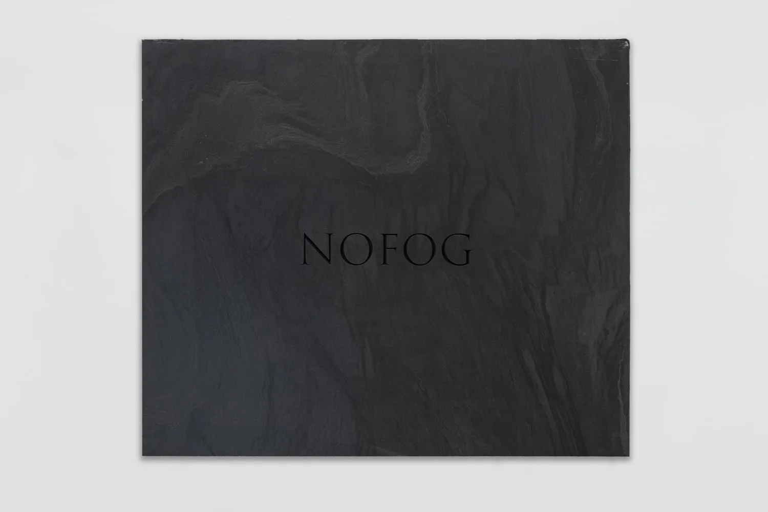JMH Schindele, NOFOG, 2026: schwarze Marmorplatte (Monte Nero) mit der Gravur „NOFOG“ in Ultraschwarz, 90 × 85 × 2 cm