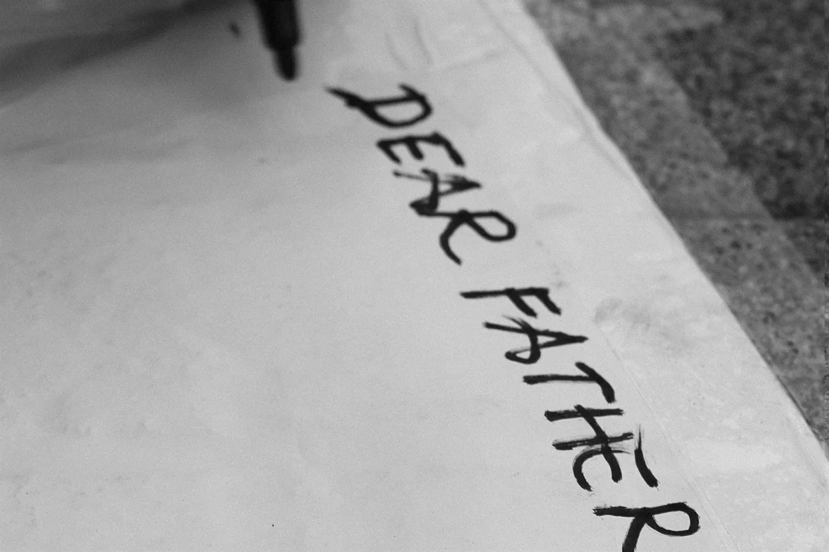 GABRIEL: die Worte „DEAR FATHER“ mit Filzstift auf Stein geschrieben, Schwarz-Weiß