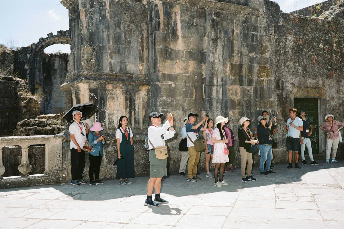 GABRIEL: Touristengruppe fotografiert vor einer Steinmauer mit Arkaden