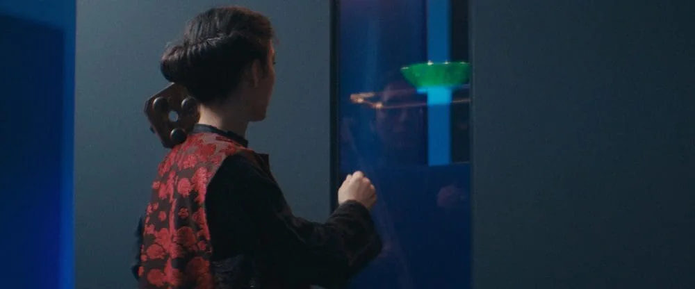 Elshan Ghasimi von hinten vor einer blau beleuchteten Vitrine im Museum
