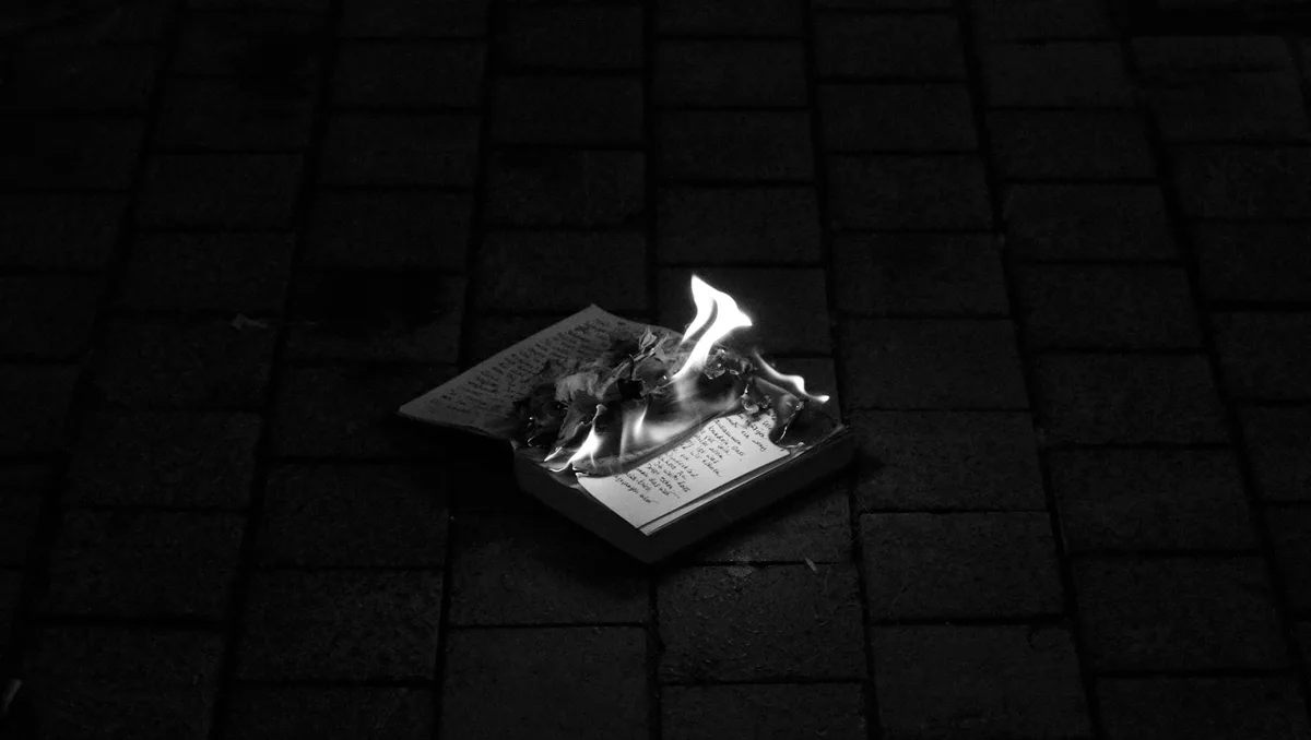 GABRIEL: ein kleines brennendes Buch auf dunklem Pflaster bei Nacht
