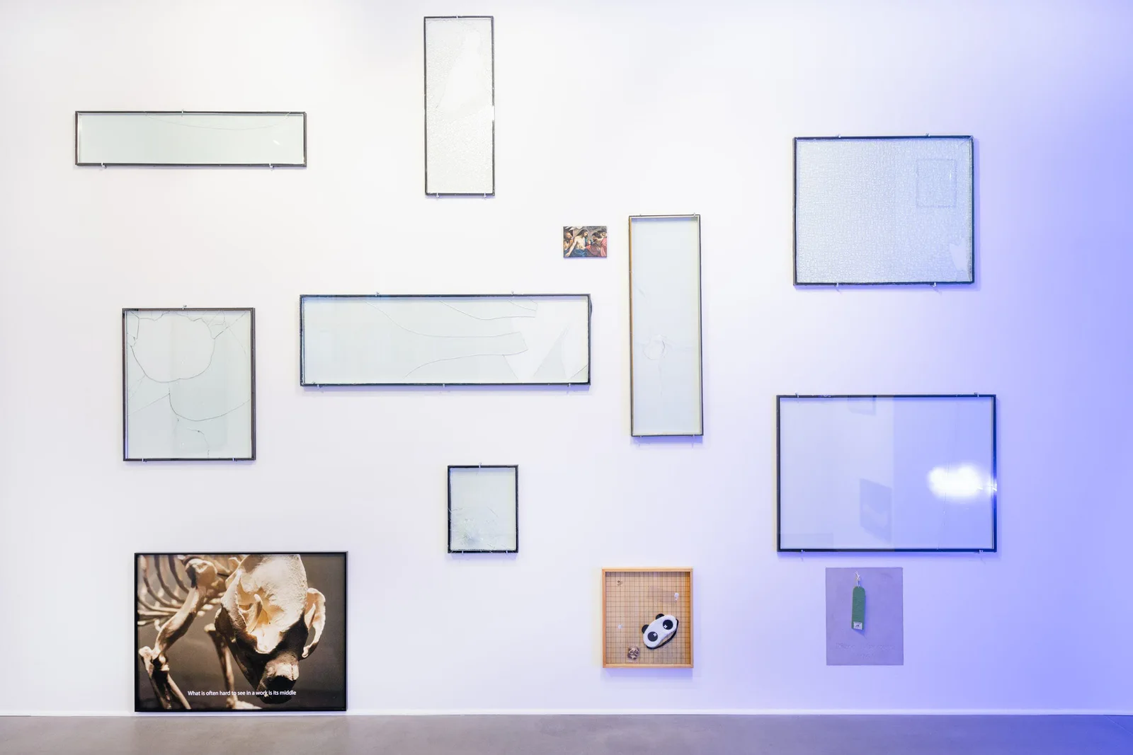 Installationsansicht: Wand mit leeren Glasrahmen, einer Panda-Fotografie und einem Go-Brett mit Pandamaske
