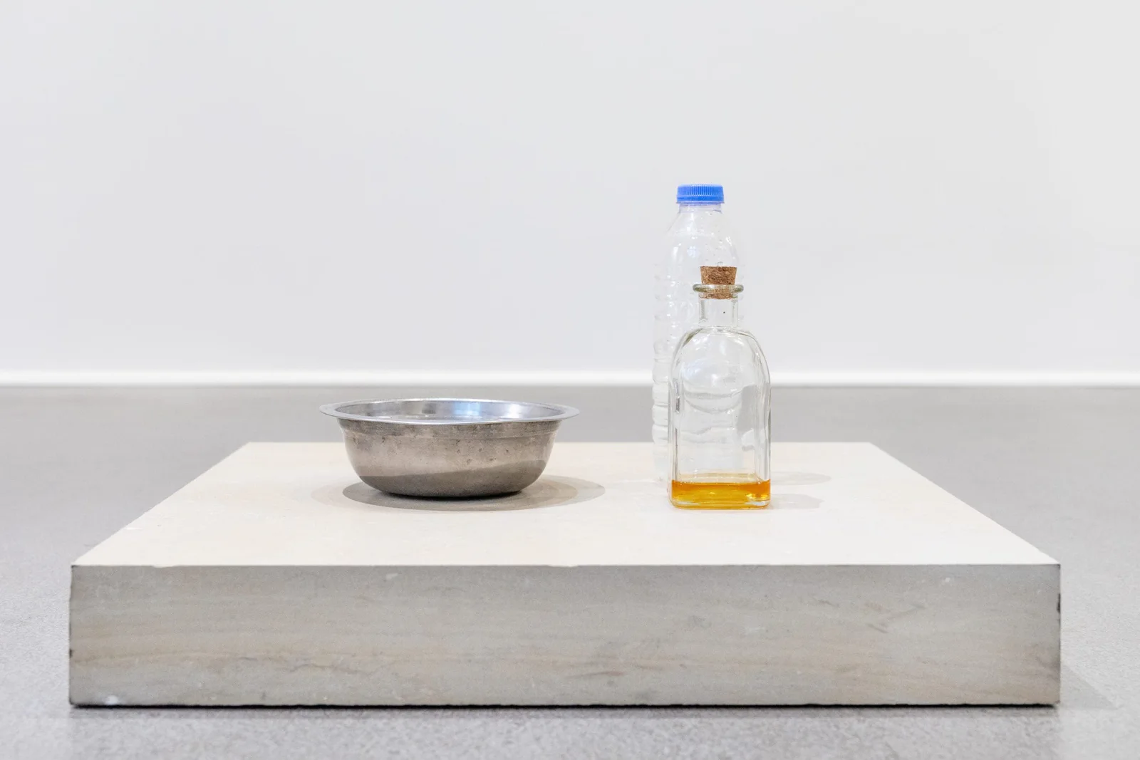 Installationsansicht: eine Schale und eine Flasche Honig auf einem flachen weißen Sockel