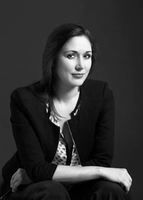Porträt von Eleonora Frolov, sitzend vor dunklem Hintergrund, Schwarz-Weiß