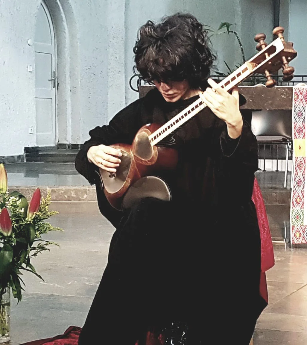 Elshan Ghasimi in Schwarz spielt die Tar in einem Kirchenraum