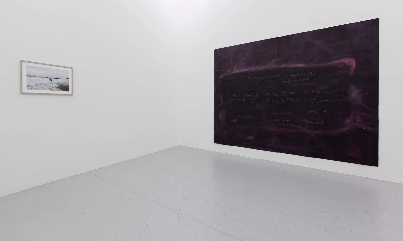 Installationsansicht mit Werken von Julius von Bismarck und Anja Langer: ein großes dunkles Gemälde und eine kleine Fotografie in einem weißen Raum