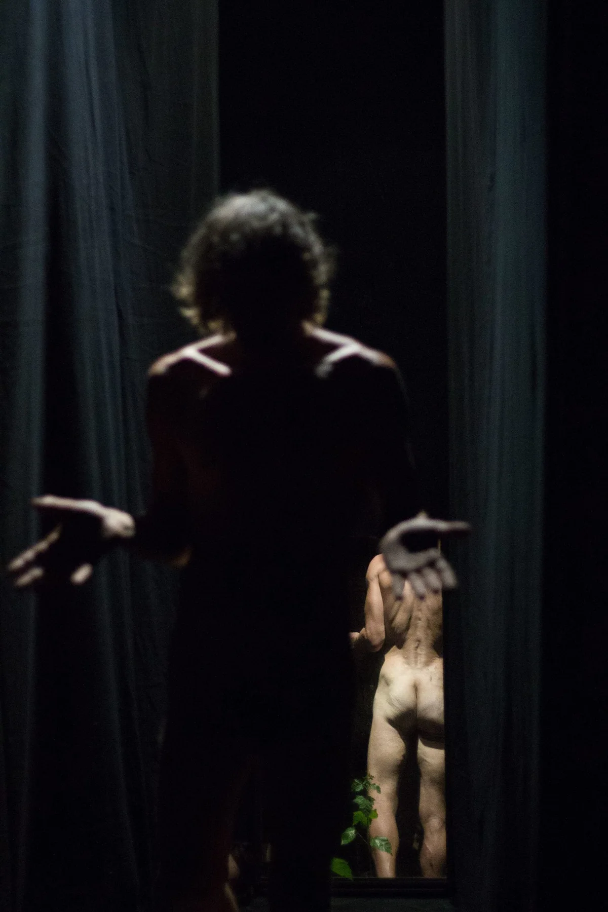 GABRIEL, Bühnenperformance: nackter Performer mit ausgebreiteten Armen zwischen schwarzen Vorhängen
