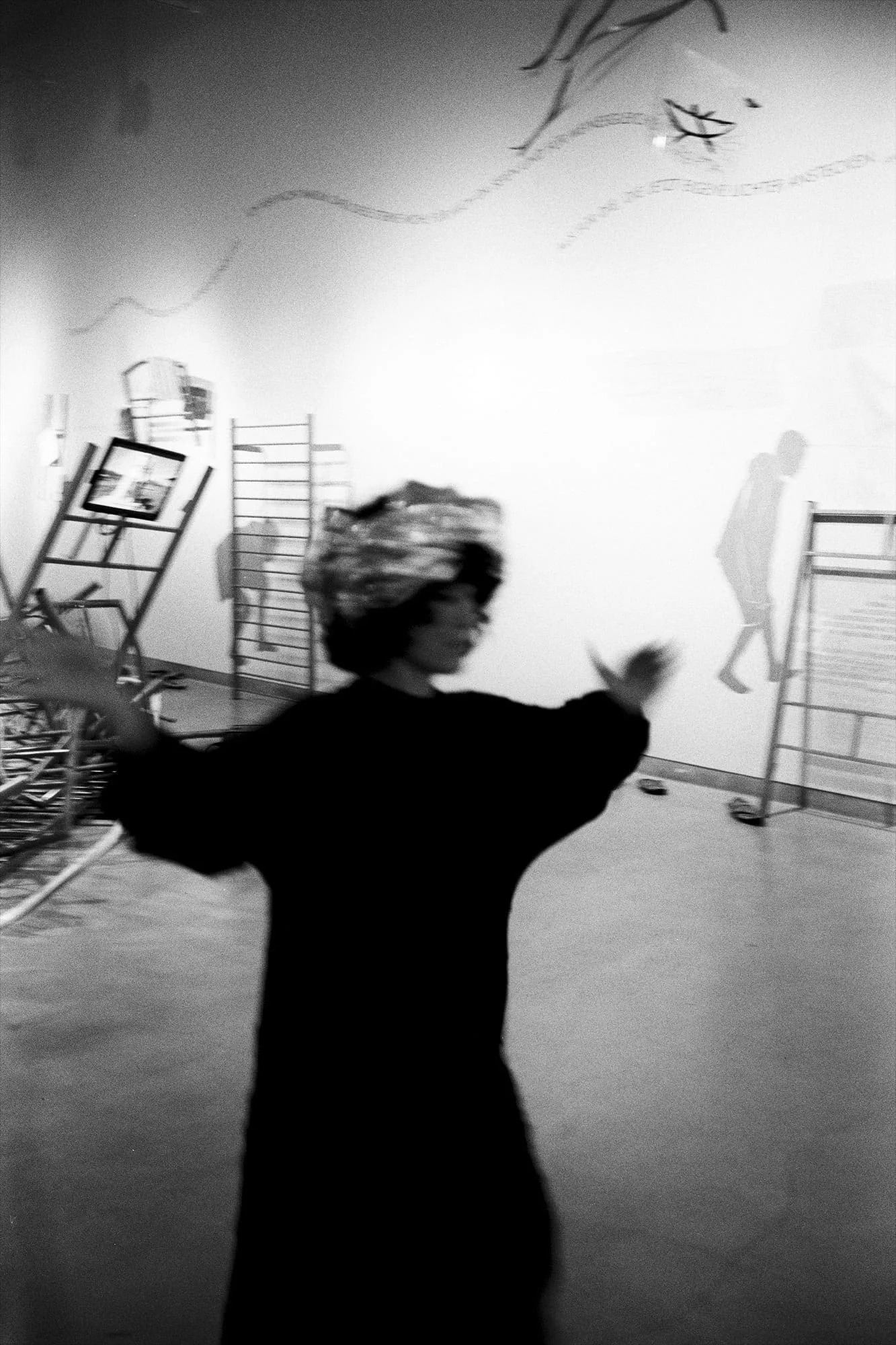 MNEMOSYNE Prelude – Die Könige: Performerin von hinten mit erhobenen Armen vor einer Projektion, Schwarz-Weiß