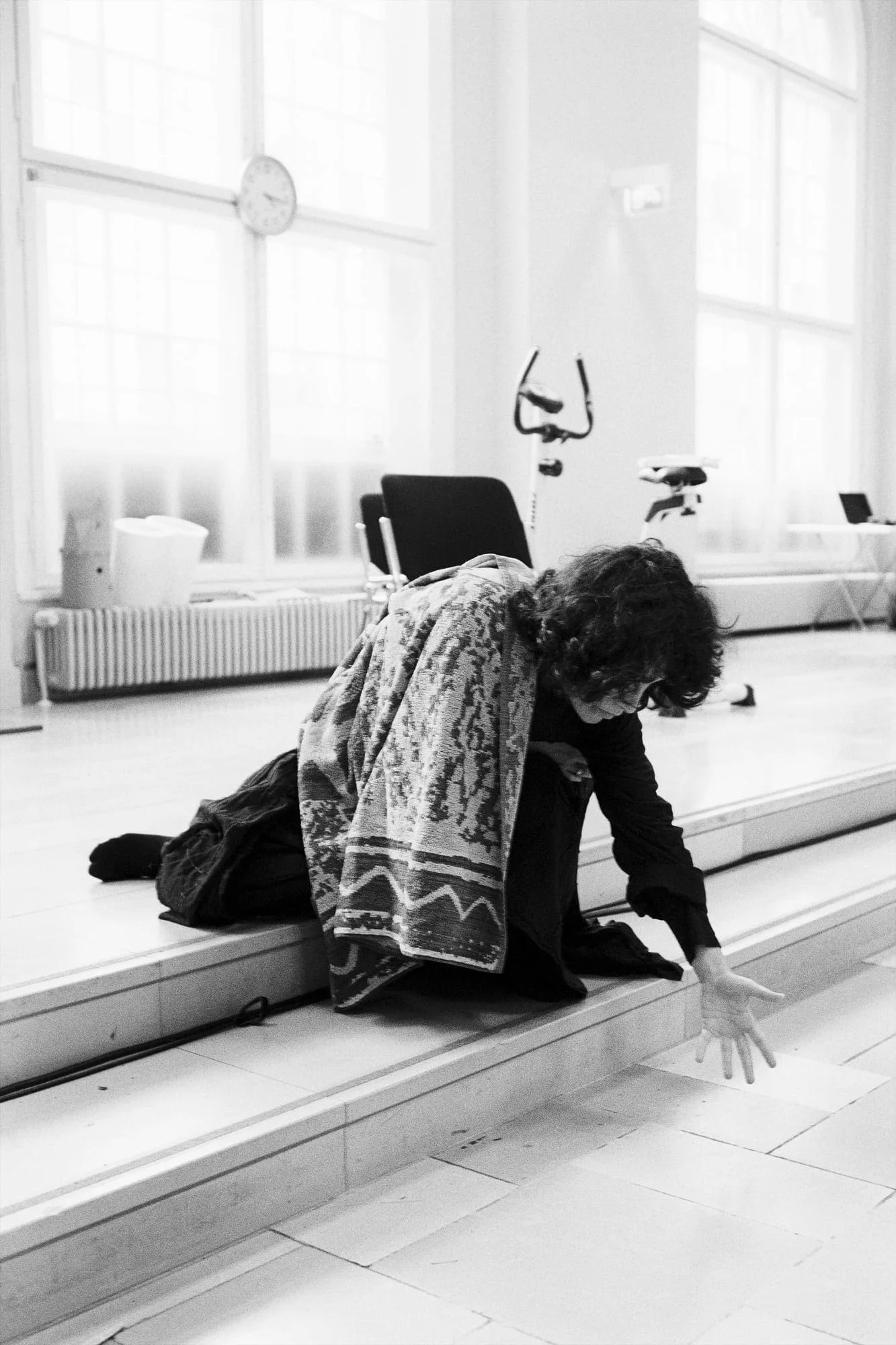 MNEMOSYNE Prelude – Die Könige: Performerin kauert vor einem hohen Fenster auf dem Boden, Schwarz-Weiß