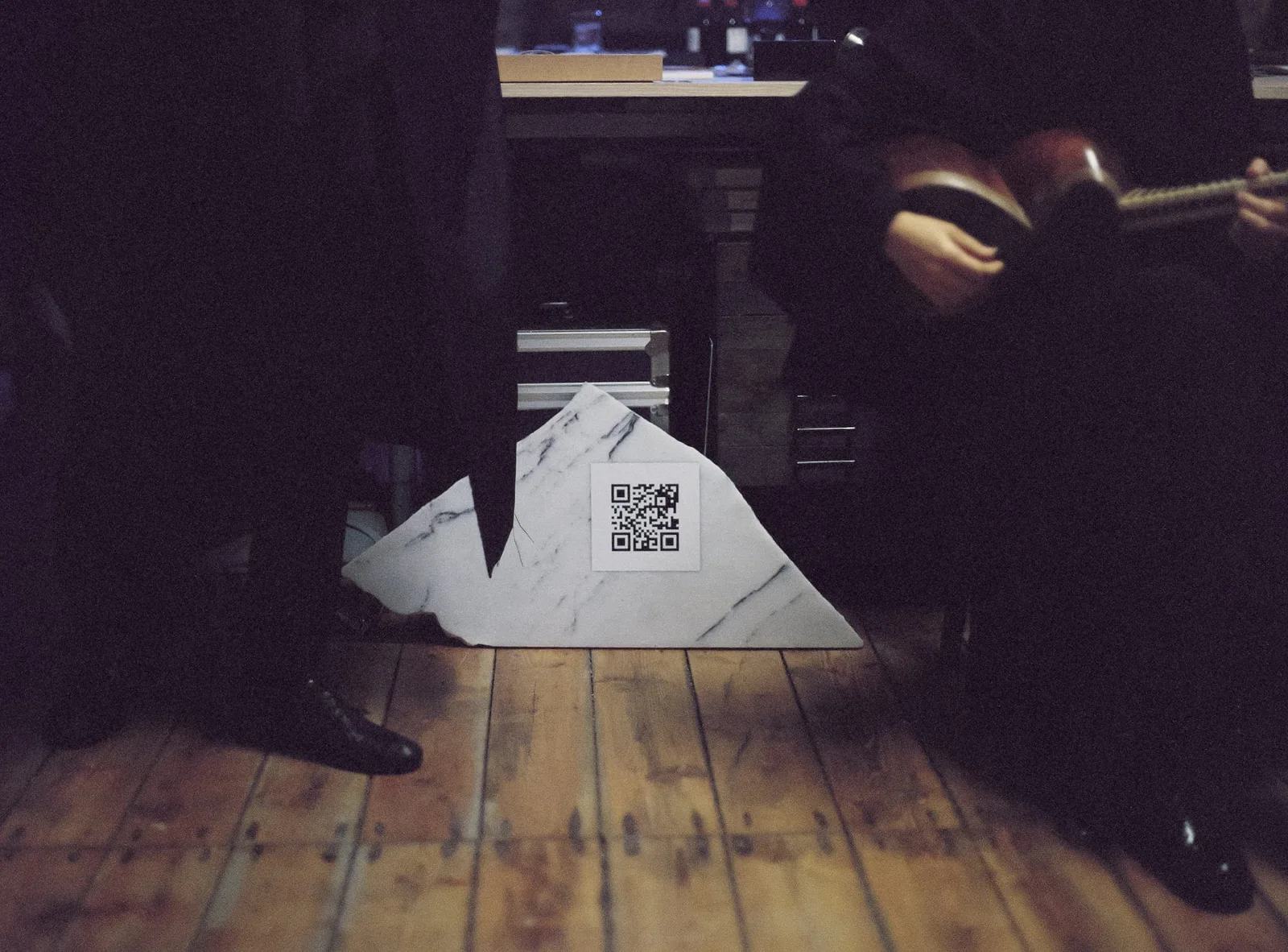 Stefan Hähnel – The Coming God: ein Marmorstück mit QR-Code auf Holzdielen, dahinter Elshan Ghasimi mit ihrer Tar
