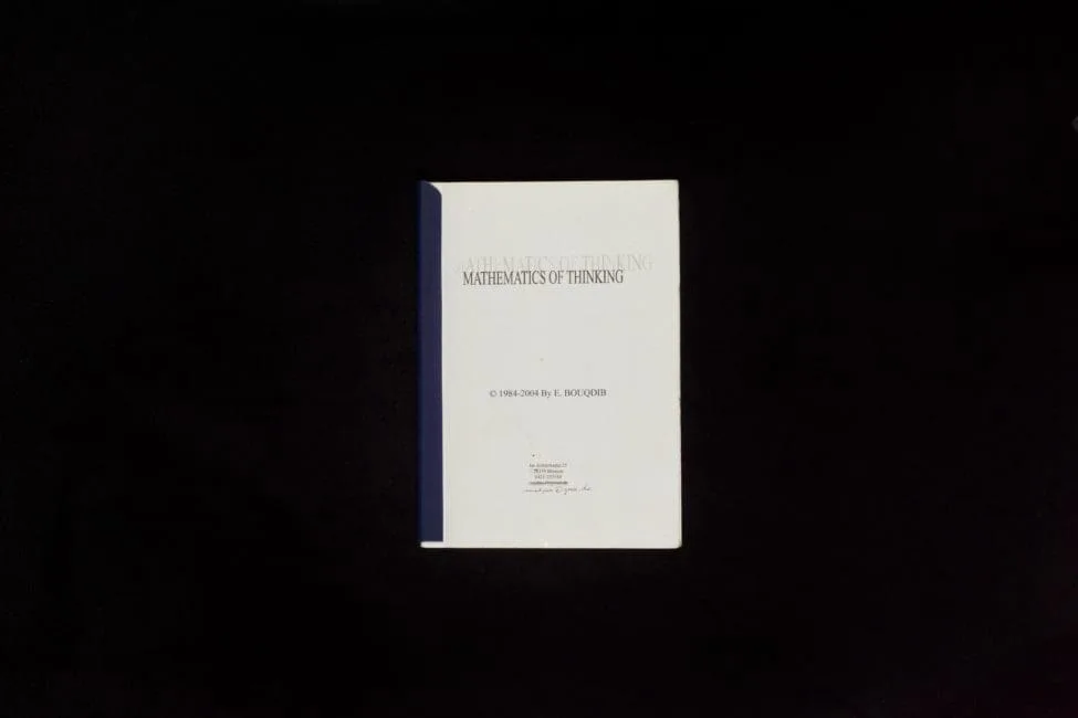 Ein weißes Heft mit dem Titel „Mathematics of Thinking, © 1984–2004 by E. Bouqdib“ vor schwarzem Hintergrund