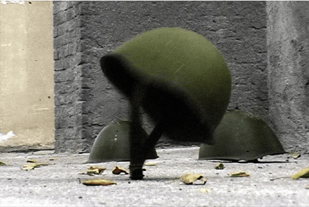 Sergey Bratkov, Endless War, 2007, Videostill: zwei grüne Stahlhelme auf Beton vor einer Mauer