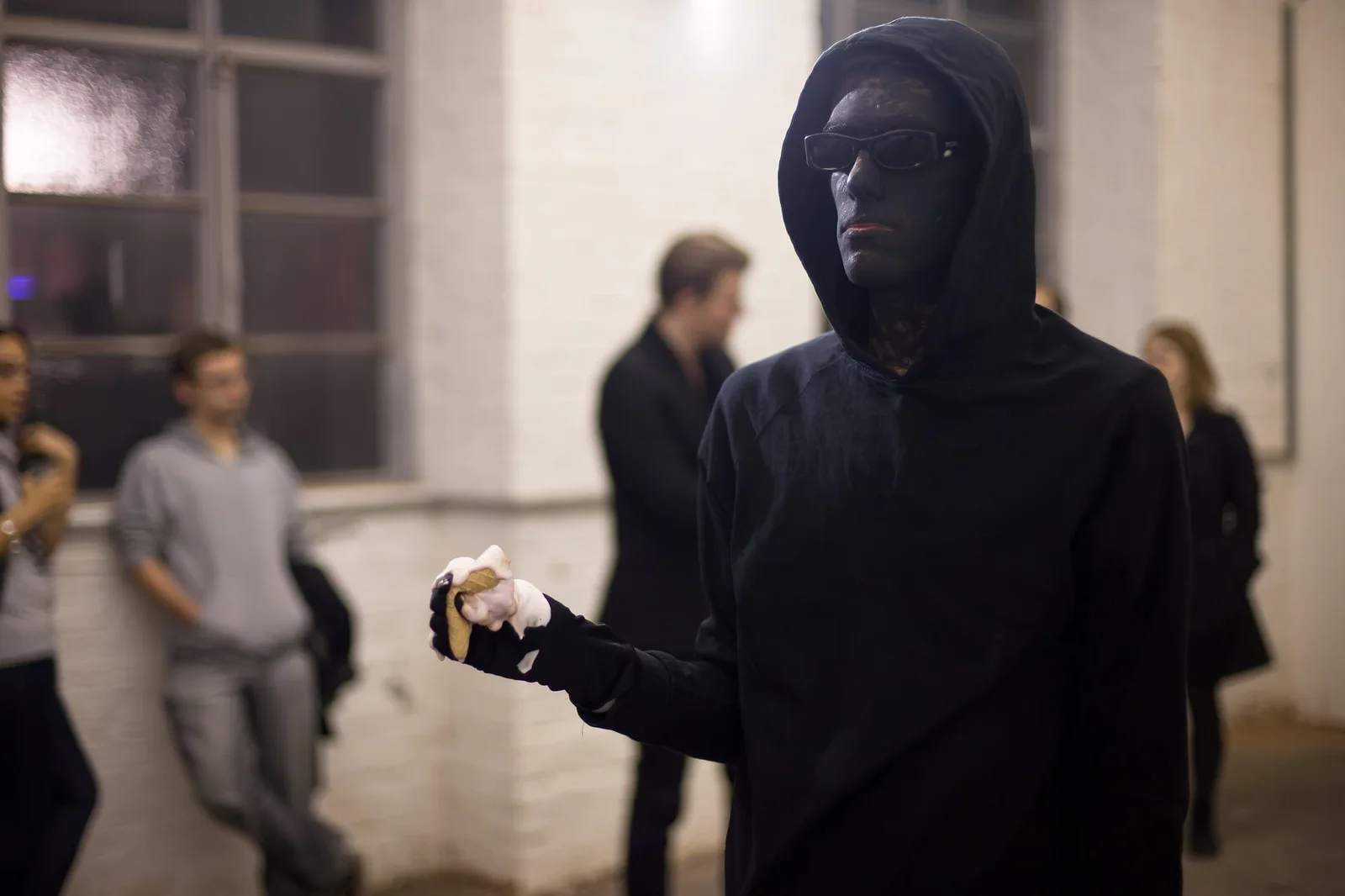 Performance von Alessandro Rauschmann – No Ice Cream: ein Performer in schwarzem Kapuzenpulli und Maske hält eine Eiskugel in der Hand