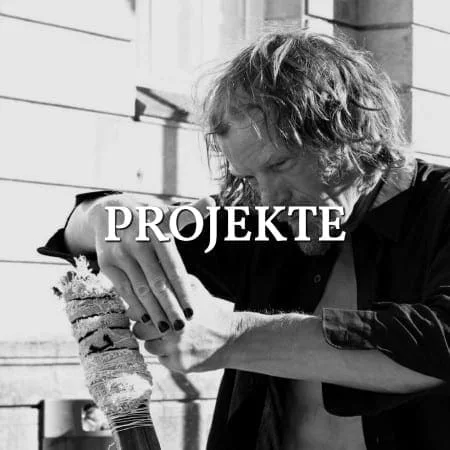 Mnemosyne Projekte: ein Mann hält eine verzierte Rolle in den Händen, Schwarz-Weiß, Schriftzug über dem Bild
