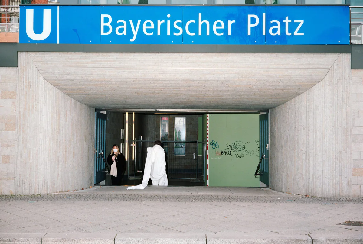 GABRIEL: Gestalt in Weiß liegt am Eingang des U-Bahnhofs Bayerischer Platz in Berlin