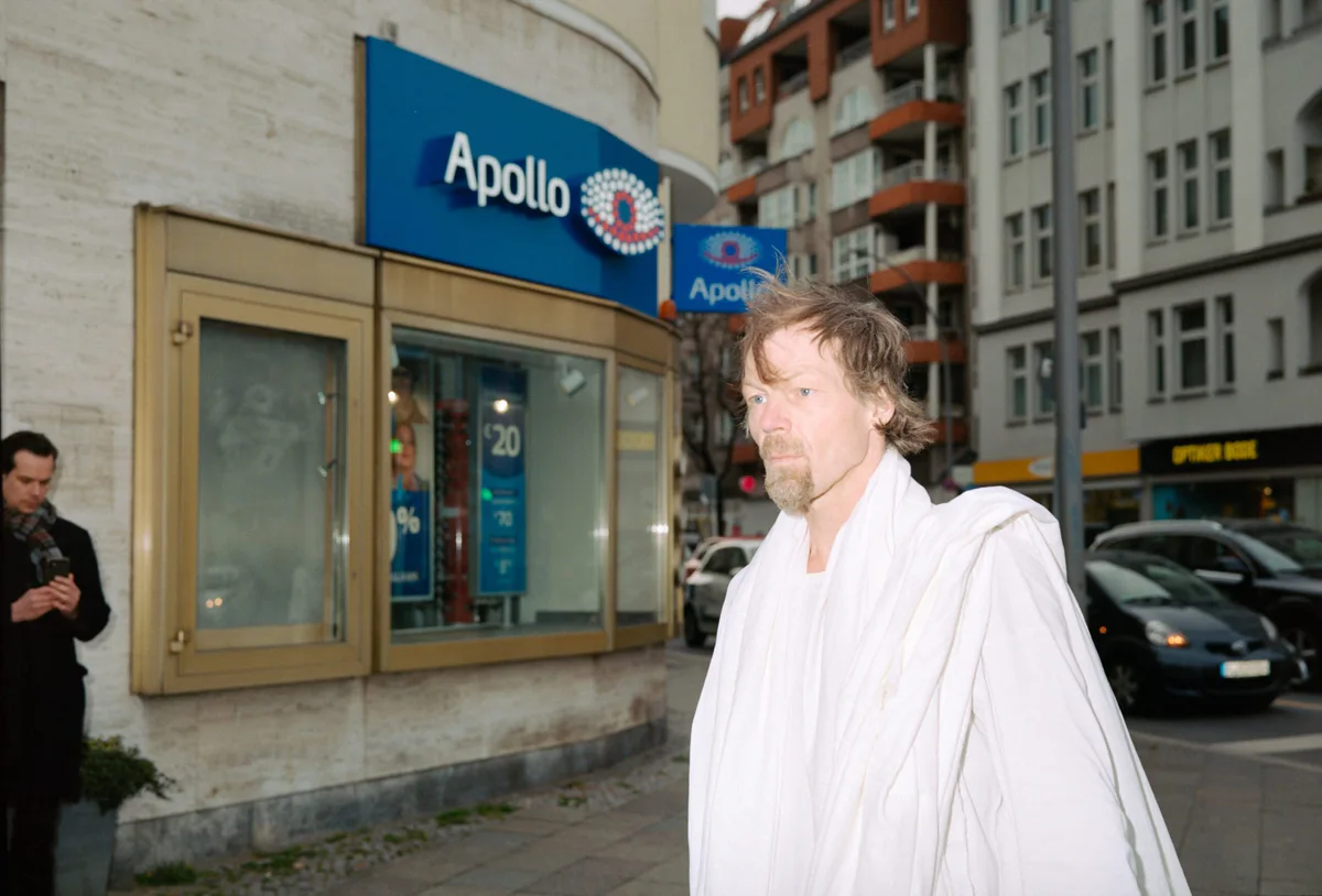 GABRIEL: Mann in weißem Tuch auf einer Berliner Straße vor einem Kinoeingang