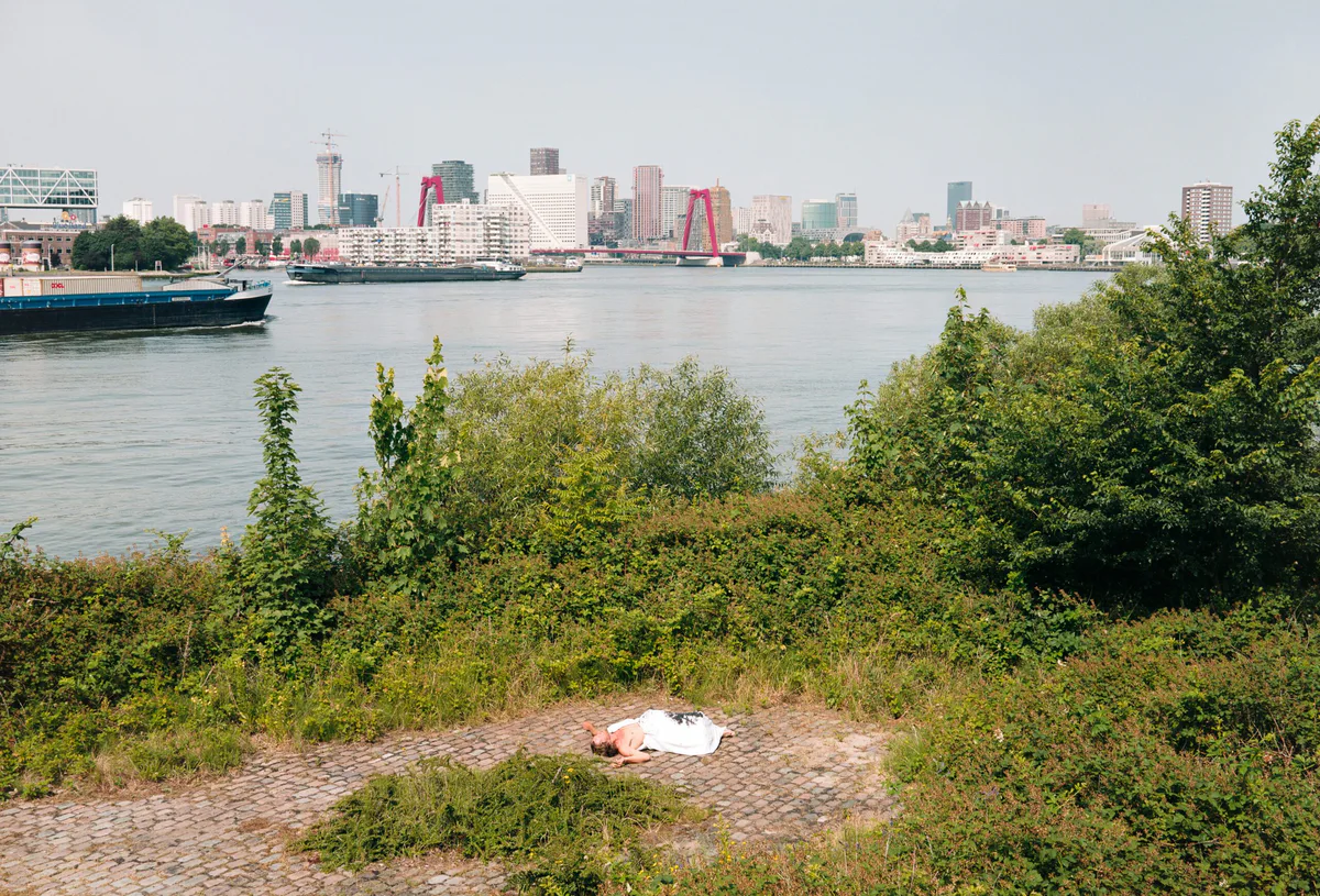 GABRIEL: weißes Bündel auf einem Kiesstrand am Fluss, dahinter die Skyline von Rotterdam