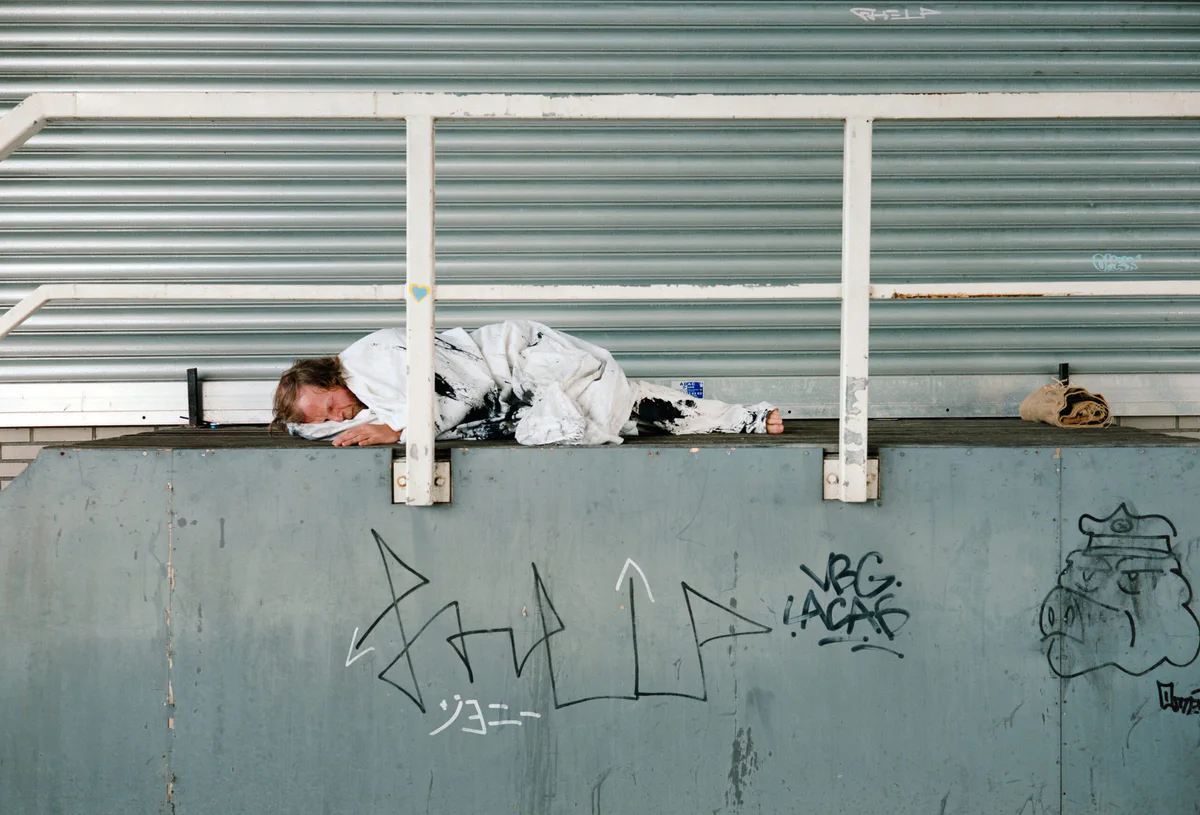GABRIEL: Mann in Weiß liegt auf einer Betonmauer mit Graffiti unter einem Geländer