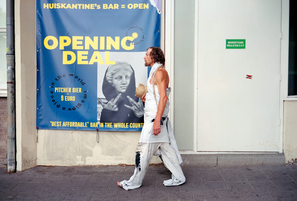 GABRIEL: Mann in weißem Gewand geht an einem Plakat „Opening Deal“ vorbei