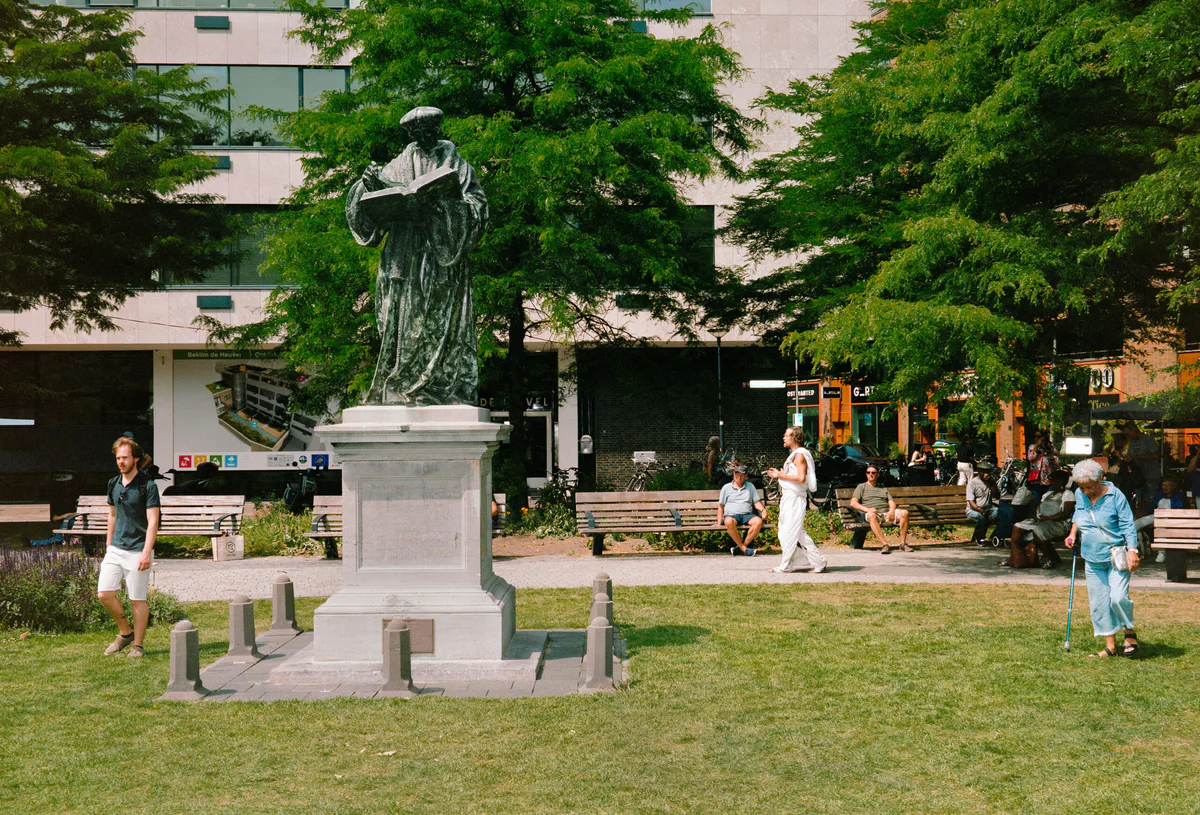GABRIEL: Mann in Weiß auf einer Wiese neben dem Denkmal einer Bronzefigur in einem Park
