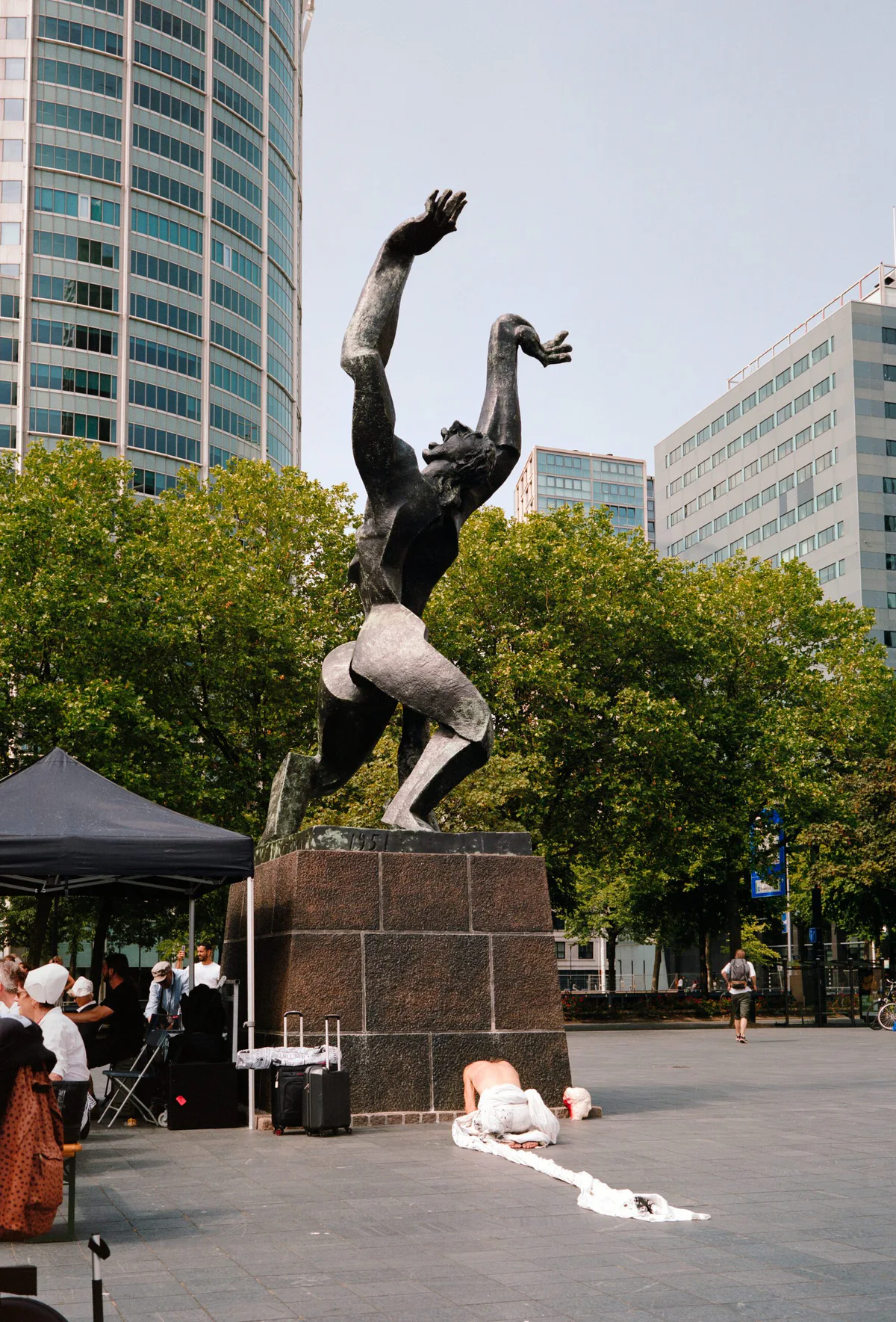 GABRIEL: Mann in Weiß liegt vor dem Denkmal „De Verwoeste Stad“ in Rotterdam