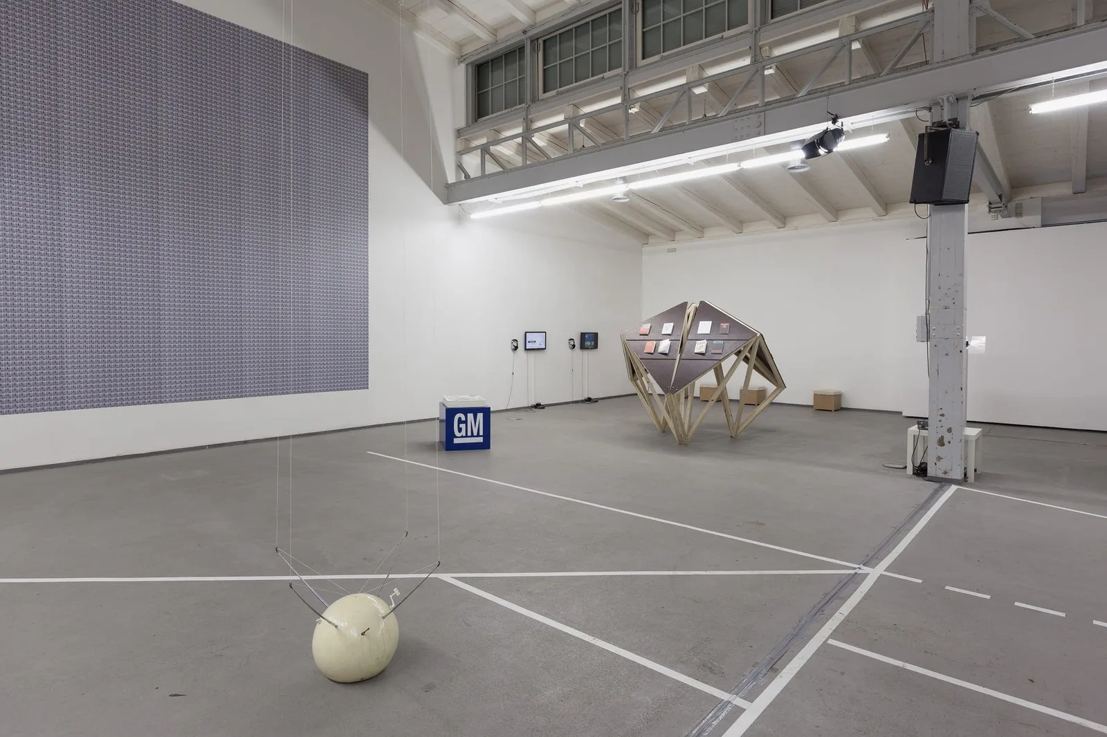 Installationsansicht: Industriehalle mit einer Kugel am Boden, einer Holzkonstruktion und einer grauen Wandfläche