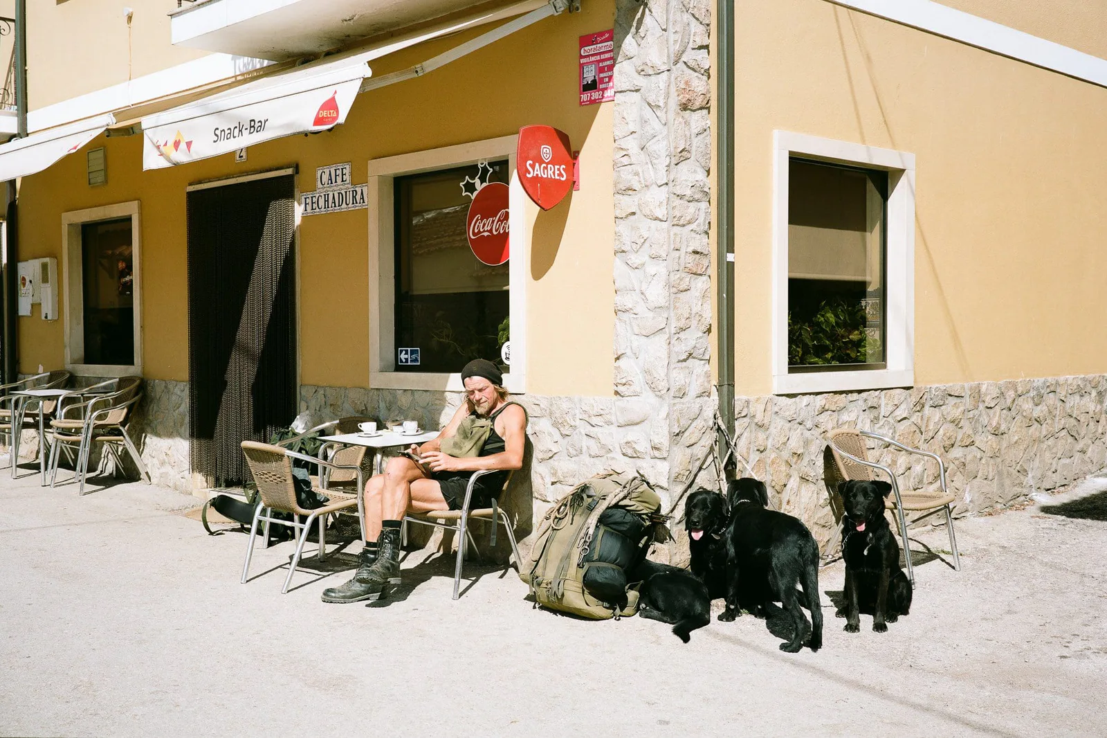 Ein Mann sitzt mit mehreren Hunden vor einem Café in der Sonne, Foto Stefan Hähnel
